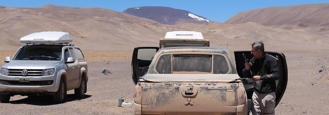 Operarios en el desierto comunicándose con un teléfono satelital